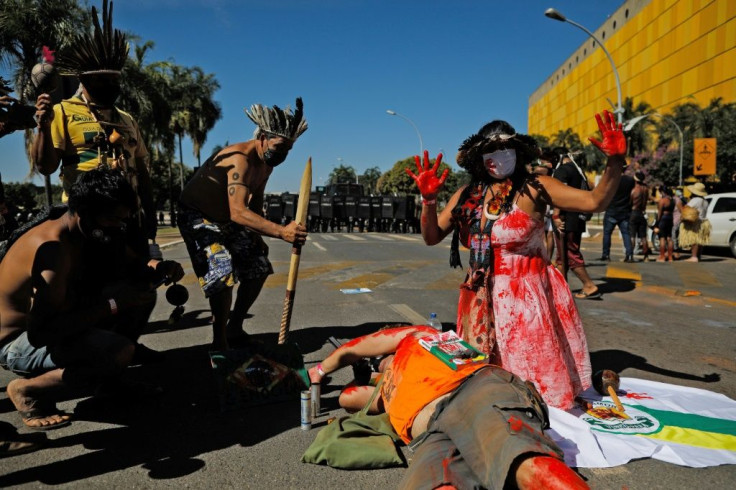 Indigenous Brazilian people act out a performance in front of riot police during a protest outside Congress in Brasilia, on June 22, 2021