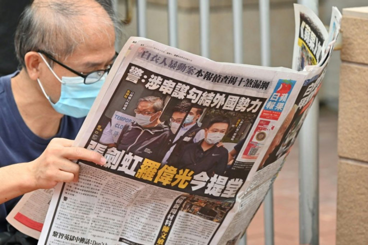 A supporter reads a copy of the Apple Daily newspaper outside a court in Hong Kong