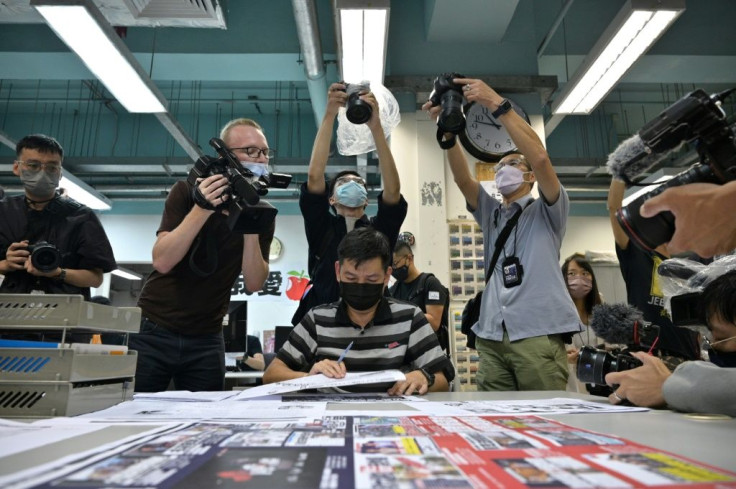 Members of the press take photos as executive editor in chief Lam Man-Chung (C) proof reads the next day's 'Apple Daily' newspaper before it goes to print for the last time