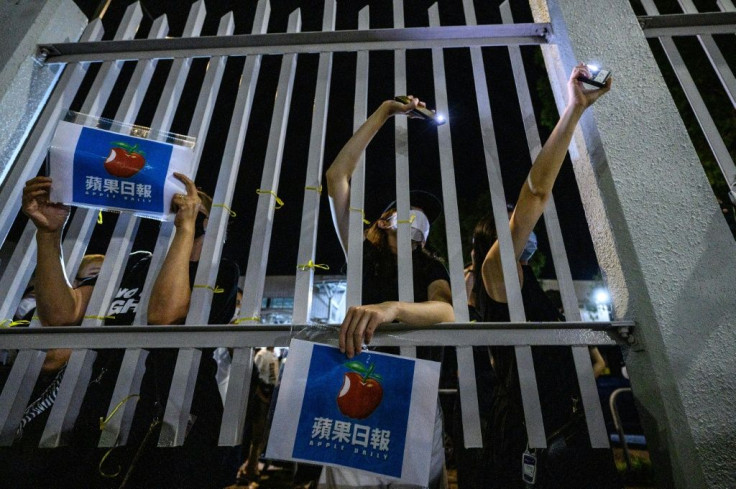 Supporters stand outside the main gate of the Apple Daily offices after the company's final newspapers were printed early on June 24