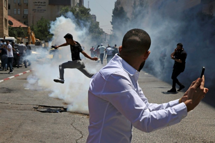 Protesters run for cover from tear gas fired by Palestinian security forces during a demonstration calling for Palestinian president Mahmud Abbas to quit