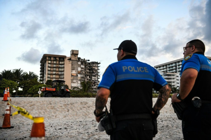 Police stand guard near the building as rescuers search the rubble for survivors