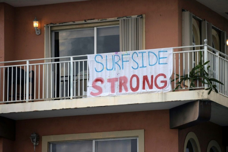 A "Surfside Strong" sign hangs on a balcony as search and rescue operations continue at the site of the partially collapsed 12-story Champlain Towers South condo building