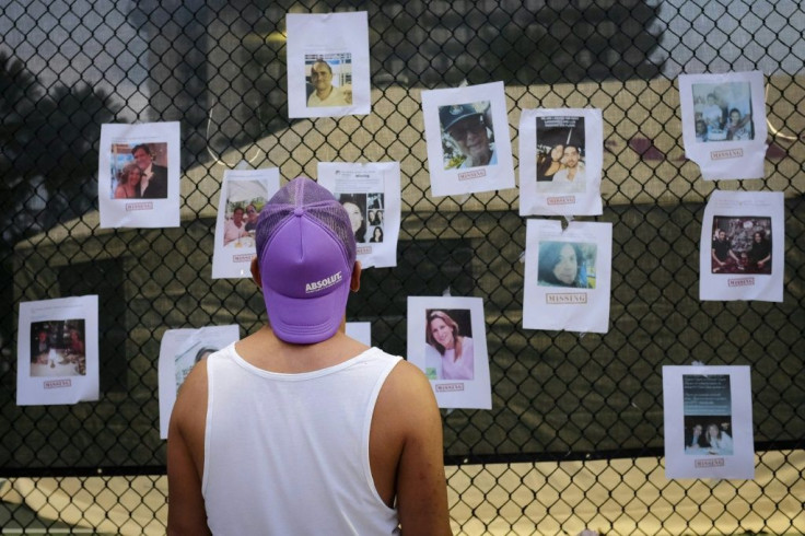 A man looks at pictures of missing residents of the partially collapsed building at a makeshift memorial in Surfside, north of Miami Beach, on June 25, 2021