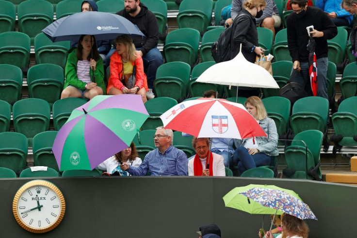 Rain pain: Spectators shelter from the rain beneath umbrellas as they wait for play to begin on the first day of Wimbledon