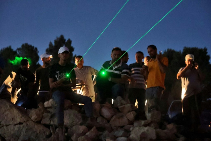 Palestinian protesters use laser torches during a demonstration against the Israeli settler outpost of Eviatar on June 28, 2021