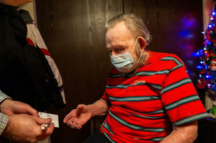RN Todd Paul hands a CDC vaccine card to Gerald McDavitt, 81, a Veteran of the United States Army Corps of Engineers