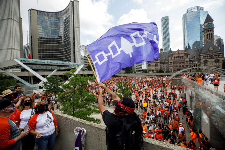A man waves the Haudenosaunee flag at Toronto City Hall during the Every Child Matters march on July 1, 2021