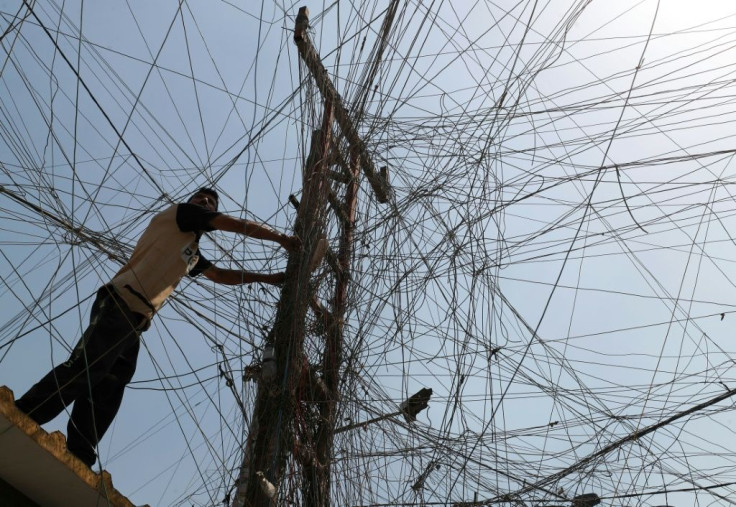 An Iraqi man connects overhead cables providing generator electricity to homes and businesses