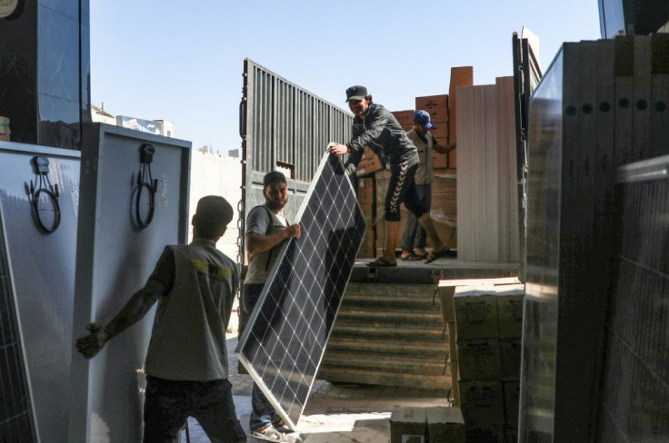 Workers unload solar panels from a truck in Dana in Syria, which provide power in areas without state-provided electricity