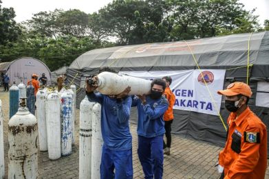 Workers unload oxygen tanks at an emergency oxygen station in Jakarta