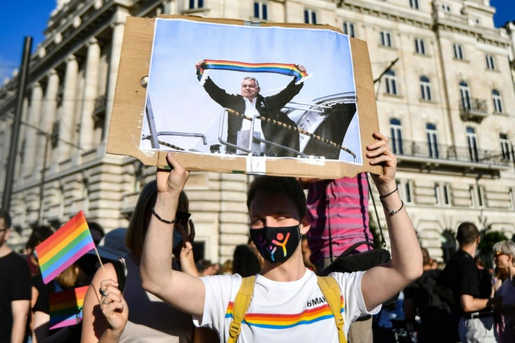 A protester demonstrating last month against Hungary's new anti-LGBTQ law holds up a picture of strongman Viktor Orban holding a rainbow scarf