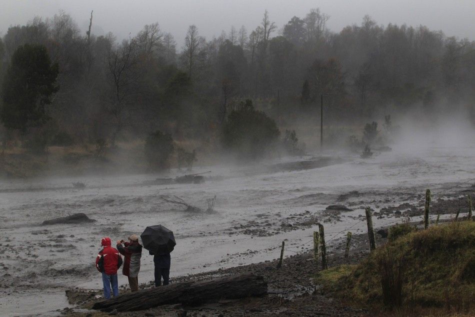 Residents watch as steam rises from the Nilhue River, fed by unusually warm water from the hot flanks of an erupting volcano from the Puyehue-Cordon Caulle volcanic chain, near Lago Ranco town