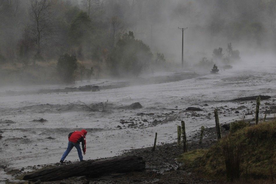 Steam rises from the Nilhue River, fed by unusually warm water from the hot flanks of an erupting volcano from the Puyehue-Cordon Caulle volcanic chain, as a resident inspects the river water near Lago Ranco town