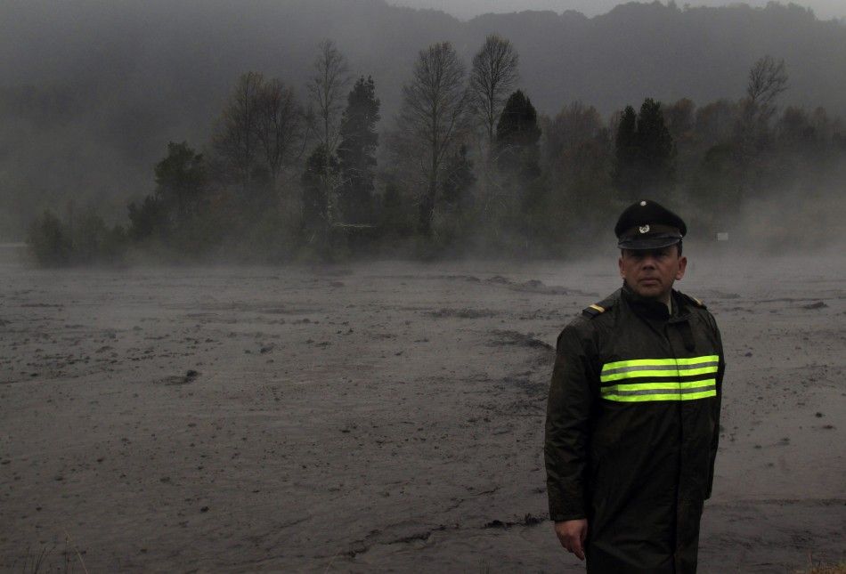 Steam rises from the Nilhue River, fed by unusually warm water from the hot flanks of an erupting volcano from the Puyehue-Cordon Caulle volcanic chain, as a policeman stands on the river bank near Lago Ranco town