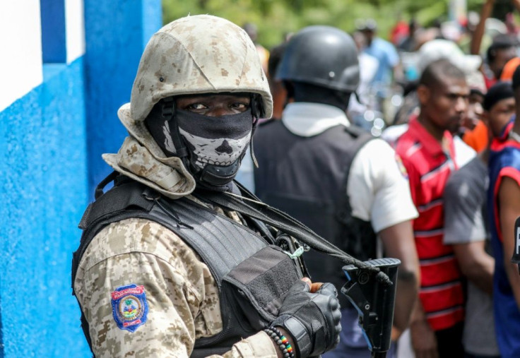 Police look on as a crowd surrounds the Petionville Police station where armed men accused of being involved in the assassination of President Jovenel Moise are being held