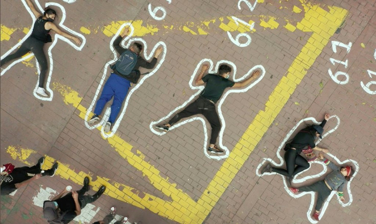 People lie on painted silhouettes simulating dead bodies, protesting for thousands of extrajudicial executions known as "false positives" and perpetrated by Colombian military forces, in Bogota on June 4, 2021