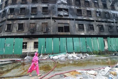 A garment worker walks past the burnt factory after the fire was put out in Rupganj, just outside Dhaka