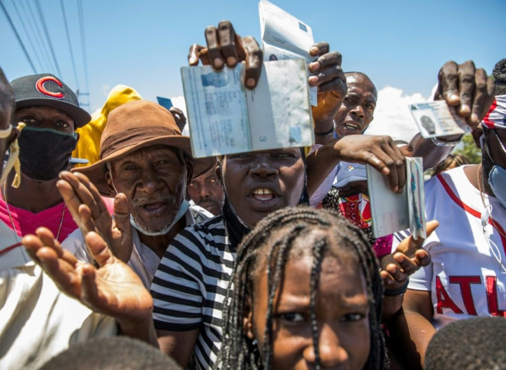 Haitian citizens hold up their passports as they gather in front of the US Embassy outside Port-au-Prince