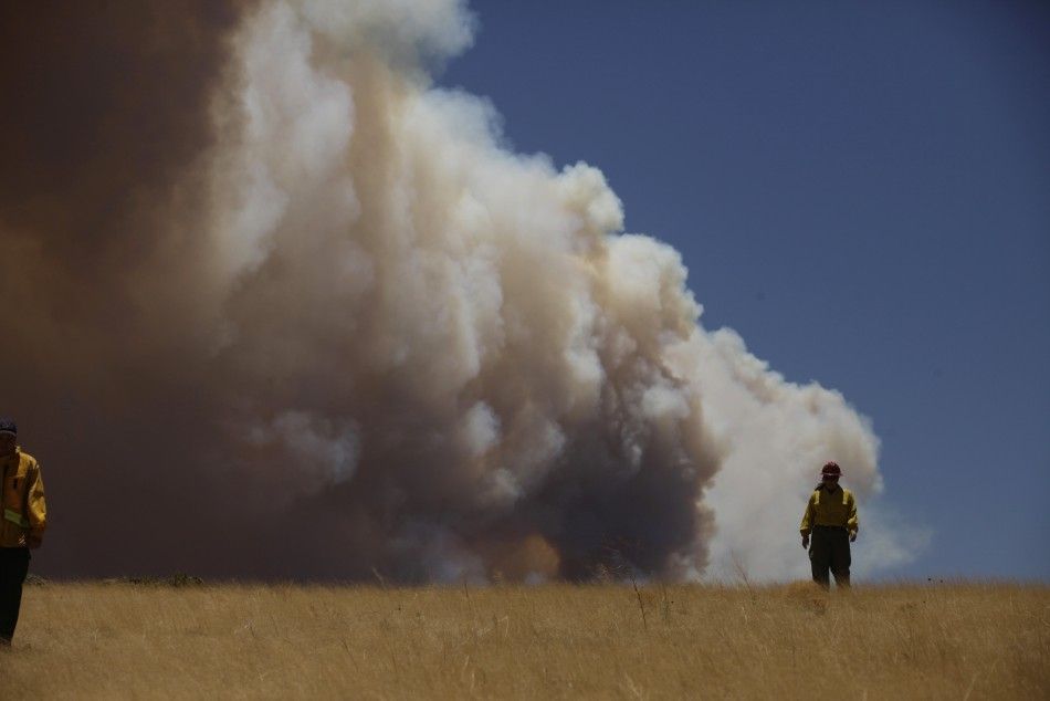 Public Information Officer Theresa Mendoza walks through a field as smoke billows over the White Mountains from the Wallow Wildfire in Apache County, Arizona 