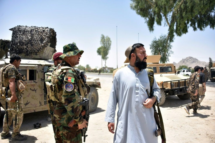 Afghan security personnel stand guard along the road amid ongoing fight between Afghan security forces and Taliban fighters in Kandahar