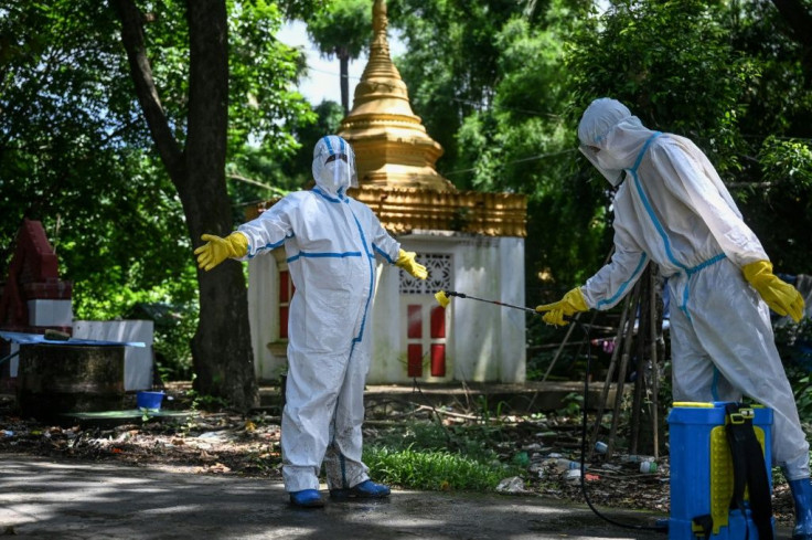 Volunteers disinfect each other after taking the body of a Covid-19 victim to a cemetery