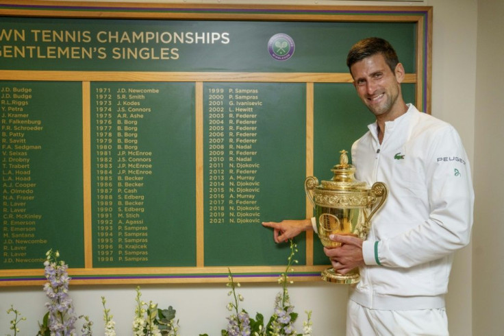 Chairman of the board! Novak Djokovic holds the winner's trophy in front of the honours board and points to his name