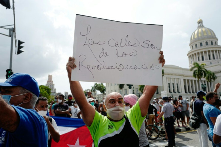 A pro-government counter-demonstrator holds a signal that reads "The streets belong to the revolutionaries" amid demonstrations against the government of Cuban President Miguel Diaz-Canel in Havana on July 11, 2021