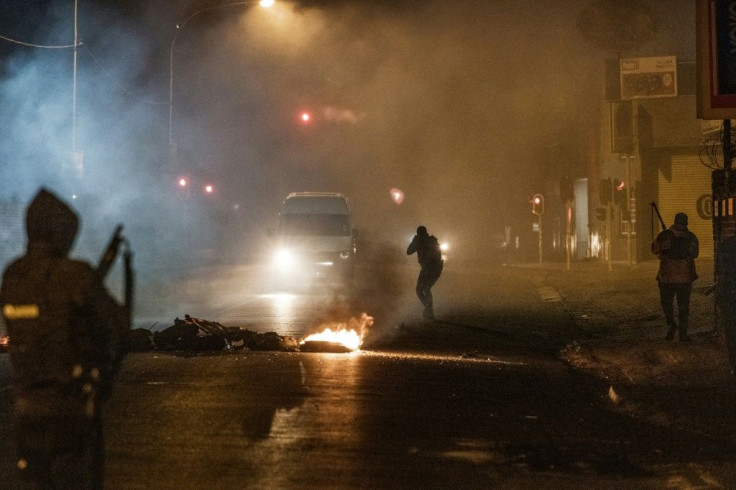 Night clashes: A police officer in the Johannesburg district of Jeppestown points his rifle at minivan, forcing it to stop