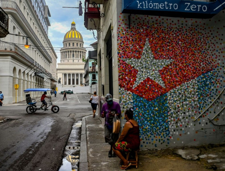 People talk near a graffiti with the Cuban flag in a street of Havana, on July 12, 2021.Thousands of Cubans took part in rare protests Sunday against the communist government.