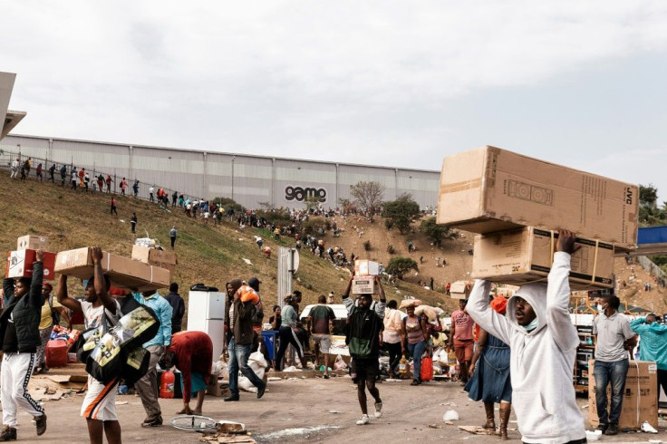 Suspected looters carry goods from the Game Warehouse in Durban