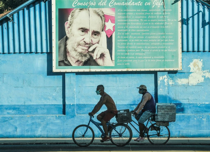 In this file photo men ride bicycles near a poster of the late Cuban leader Fidel Castro in Havana, on July 12, 2021