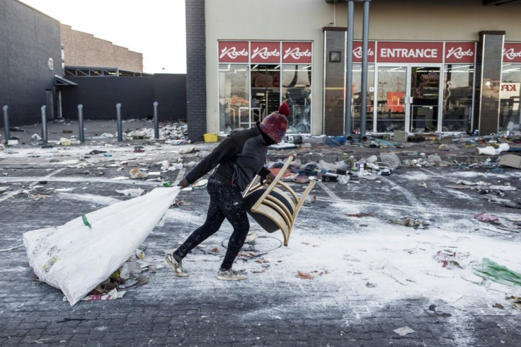 A suspected looter hauls away items on Wednesday from a ransacked shopping mall in Vosloorus on the outskirts of Johannesburg
