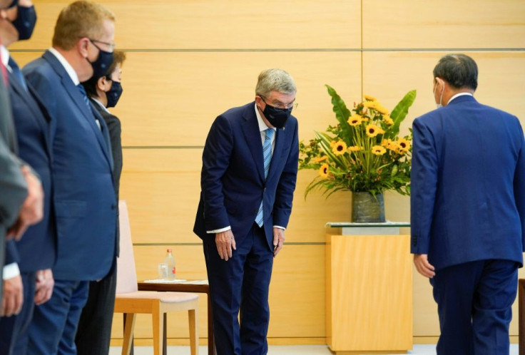 IOC president Thomas Bach (C) bows to Japan's Prime Minister Yoshihide Suga (R)