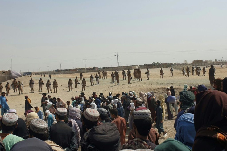 Pakistani border guards cordon off the area as stranded people gather near a border crossing between Afghanistan and Pakistan in Chaman