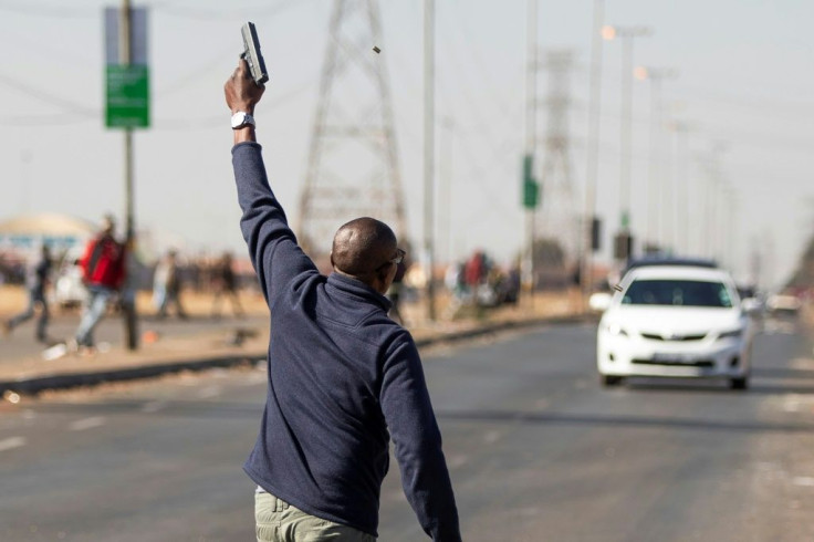 A man fires a gun in the air to disperse suspected looters outside a mall in the Johannesburg suburb of VosloorusUnrest raged in South Africa on July 14, 2021, for the sixth day running, stoking fears of food and fuel shortages as disruption to farming