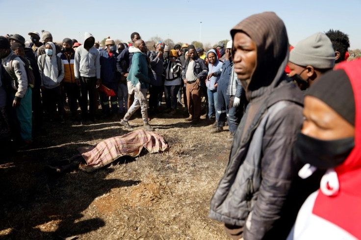 People stand around the body of a 12-year old boy allegedly shot by taxi drivers shielding the Chris Hani Mall in Vosloorus