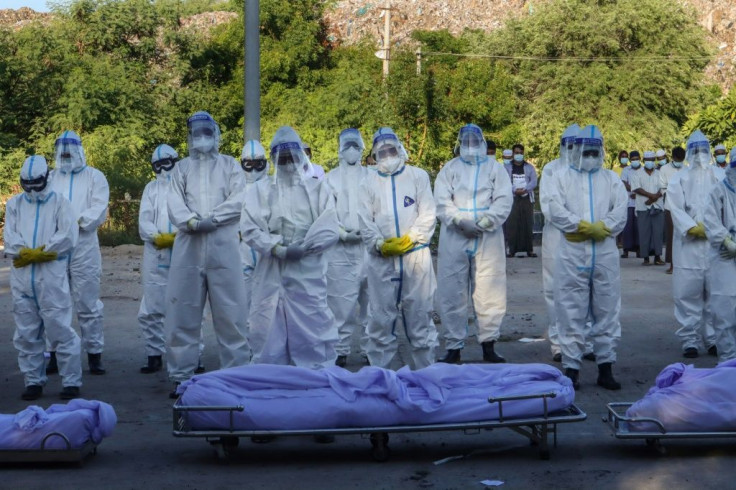 Volunteers wearing personal protective equipment pray in front of the bodies of people who died from Covid-19 during their funeral at a cemetery in Mandalay, Myanmar