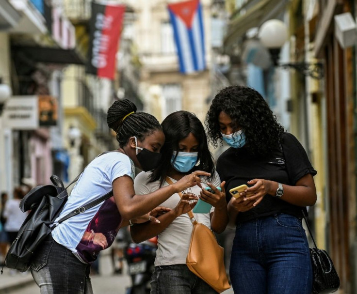 Three women in Havana check their mobile phones after internet access was restored in Cuba
