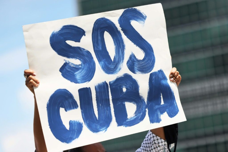 A protester in New York brandishes a sign with the SOS Cuba phrase that became a Twitter hashtag, which Cuba's government blames for unprecedented demonstrations