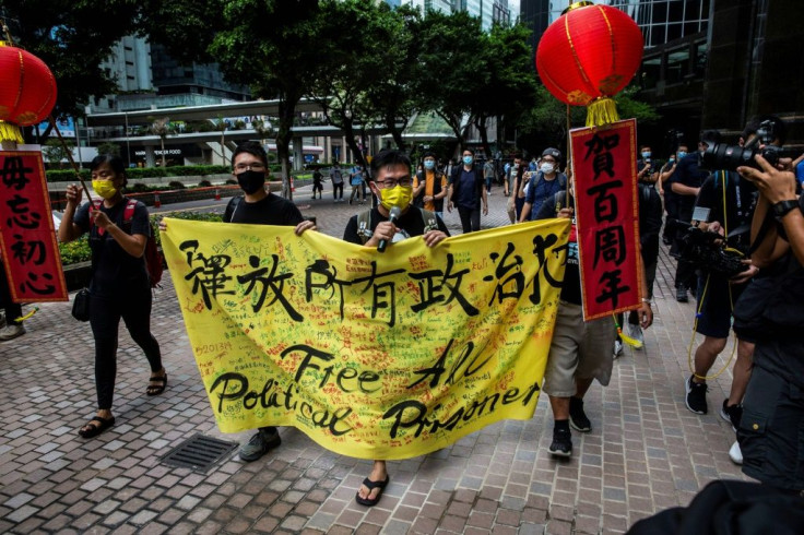 Pro-democracy activist Raphael Wong from the League of Social Democrats marches during a protest in Hong Kong on July 1, 2021, while a flag-raising ceremony to mark the 24th anniversary of Hong Kong's handover from Britain is held nearby