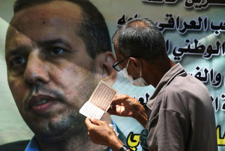 An Iraqi man recites verses from the Koran next to a poster of Iraqi jihadism expert Hisham al-Hashemi in this July 2020 photograph