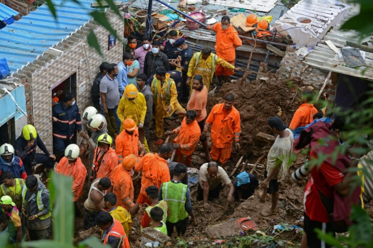 Rescue workers inspect the rubble left after a falling tree demolished a wall in the suburb of Chembur, Mumbai