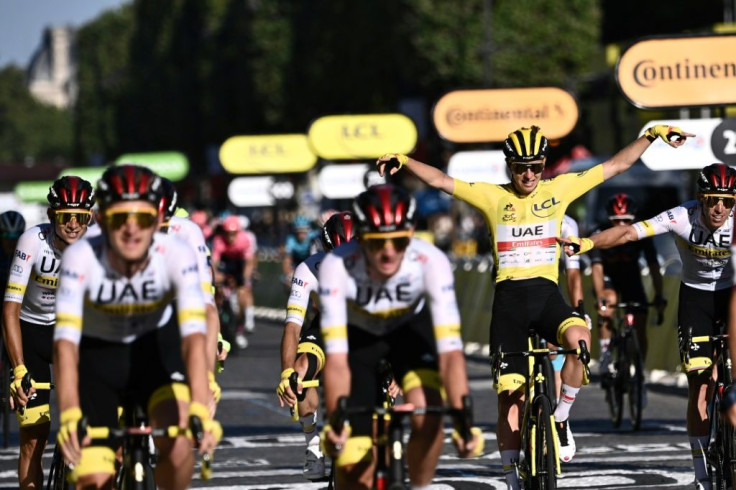 Tadej Pogacar celebrates crossing the line on the Champs-Elysees