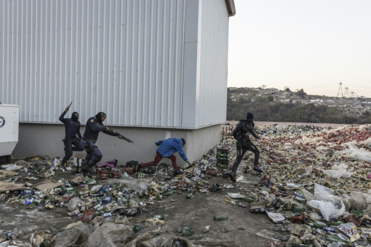 Police chase and shoot rubber bullets at two suspected looters outside a warehouse storing alcohol in Durban
