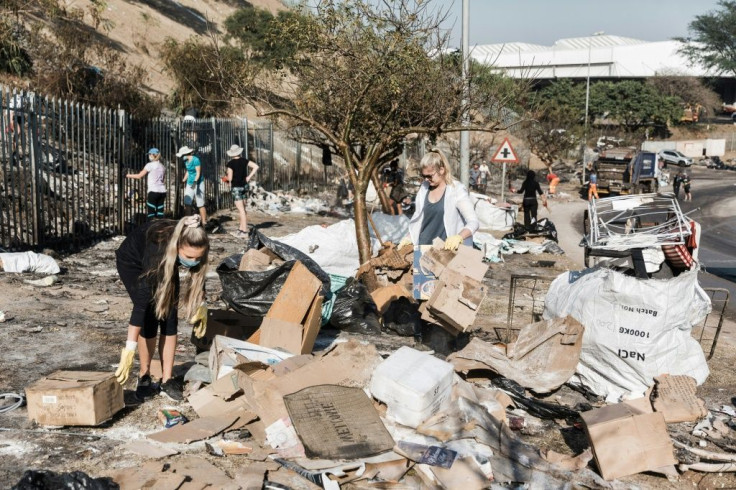 Local community members clean up debris from the floor in the aftermath of continuous looting and destruction at the Queen Nandi Drive in Durban