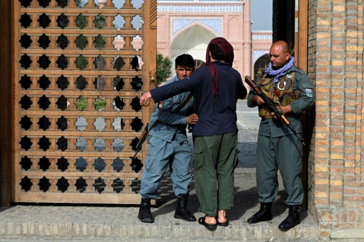 An Afghan security personnel frisks devotees at the entrance of a mosque during the Eid al-Adha prayers in Kabul