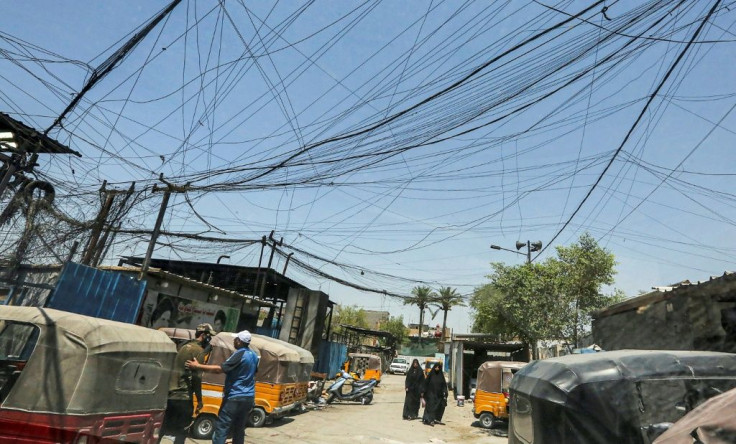 Iraqis walk under a labyrinth of cables linking homes to private electric generators in Baghdad's Sadr City