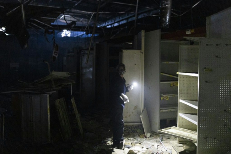 Aftermath: A woman uses a torch to clear debris at a looted shop in Durban's Dube Village Mall