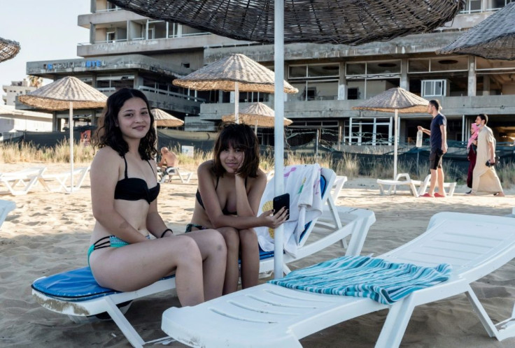 Tourists pose for a picture in the fenced-off area of Varosha in Famagusta town in the self-proclaimed Turkish Republic of Northern Cyprus in June 2021